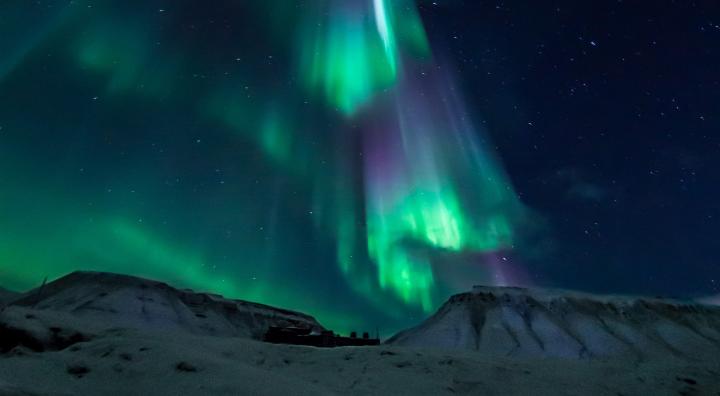 northern lights shining above a snowy Norwegian mountain
